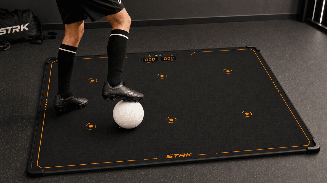 Young football player training with ball control cues on the STRK mat